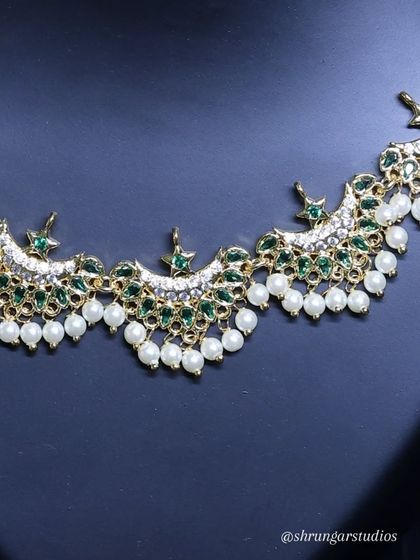 A close-up of the intricate design and the combination of green stones and pearls.