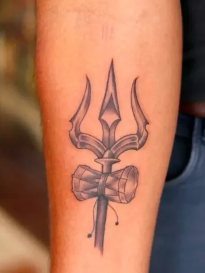 A simple yet strong Trishul and Damru tattoo on the forearm. This black and grey piece is a clear and bold symbol of devotion to Lord Shiva.