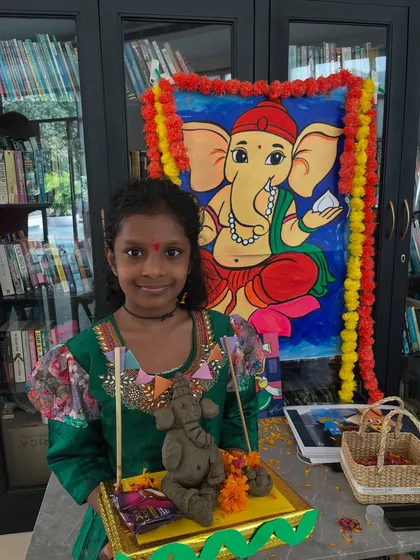 This student proudly displays her finished Ganesha, complete with a decorated thali and a festive backdrop.