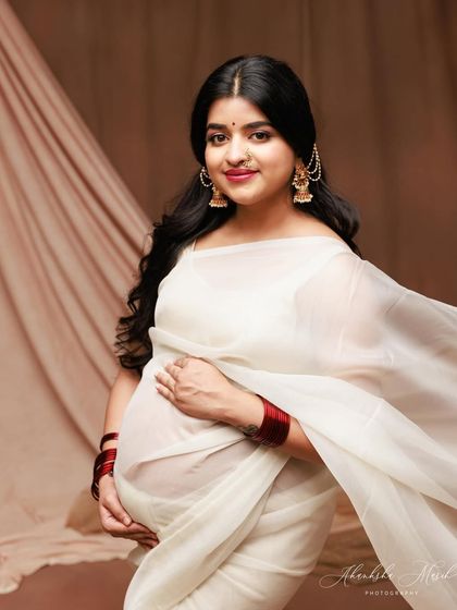 A classic and radiant portrait in a white saree, capturing a direct and engaging gaze that is full of warmth and happiness.