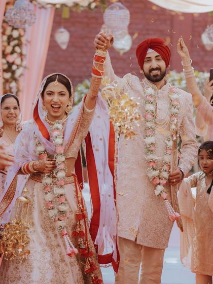 A moment of pure celebration as the Sikh bride and groom walk together, their hands raised in joy after the Anand Karaj.