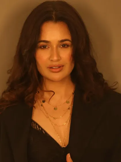 A warm, glowing portrait. The lighting enhances the radiant finish of the makeup, giving her skin an ethereal quality.