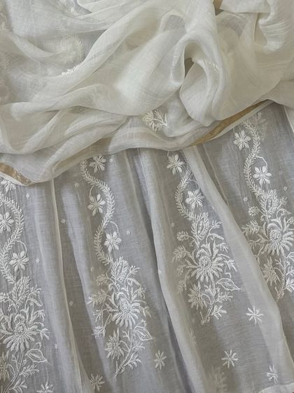 A close-up of the Anarkali's flare, highlighting the delicate floral butis and vine-like patterns that adorn the lower half of the dress.