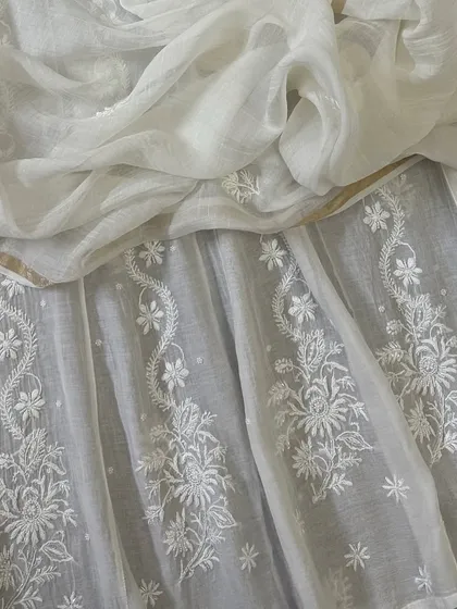 A close-up of the Anarkali's flare, highlighting the delicate floral butis and vine-like patterns that adorn the lower half of the dress.