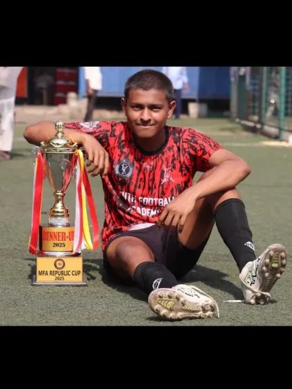 A moment of reflection after a hard-fought final. This player sits with the MFA Republic Cup runner-up trophy, a symbol of the team's resilience.