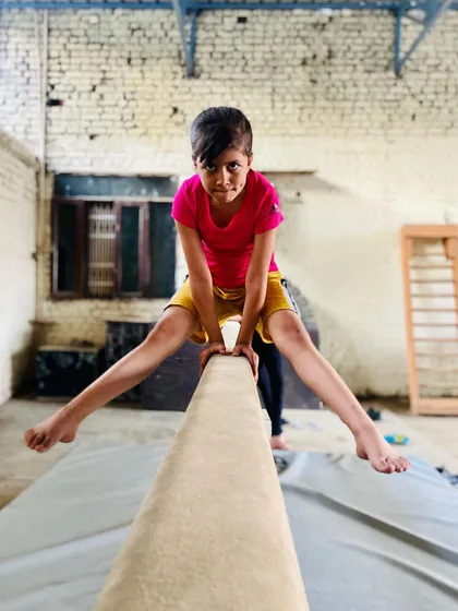 This young gymnast shows great confidence and flexibility while practicing a split on the balance beam. This is a foundational skill for artistic gymnastics.