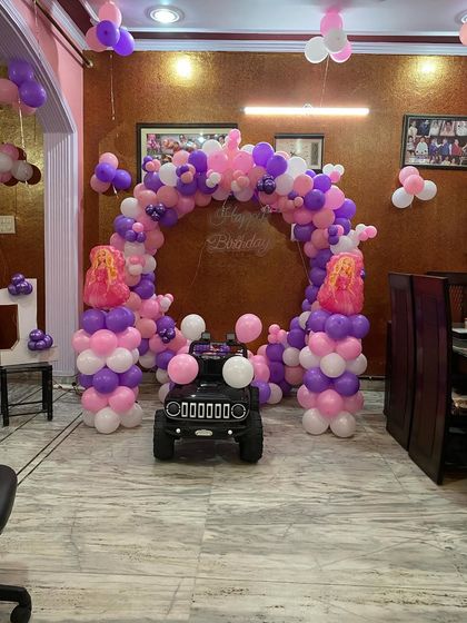 A fun addition to the princess-themed party, a small toy jeep is parked in front of the balloon arch, ready for the birthday girl.