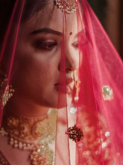 A close up, artistic shot of a bride through her pink veil. This photo captures a moment of quiet contemplation and highlights the delicate details of her look.
