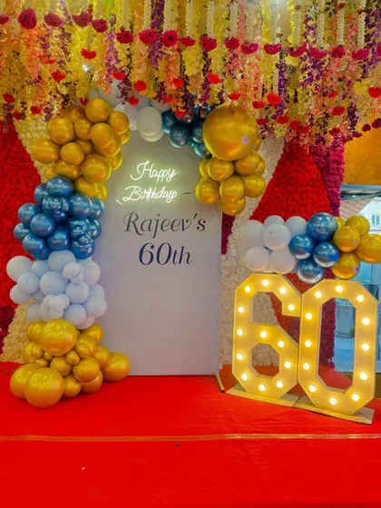 A grand 60th birthday celebration with a custom backdrop, marquee numbers, and a blue and gold balloon arrangement.