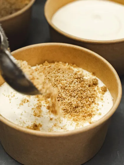 Sprinkling biscuit crumble over a layer of cream in our dessert cups.