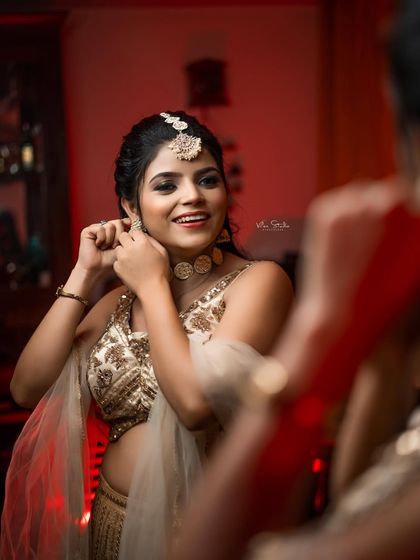 A candid moment of the bride getting ready, adjusting her earring while looking in the mirror. Her happy expression shows the excitement of the wedding day.