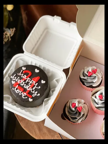 Another angle of the 21st birthday combo, showing the rich dark chocolate bento cake and the swirled black and white cupcakes ready for gifting.