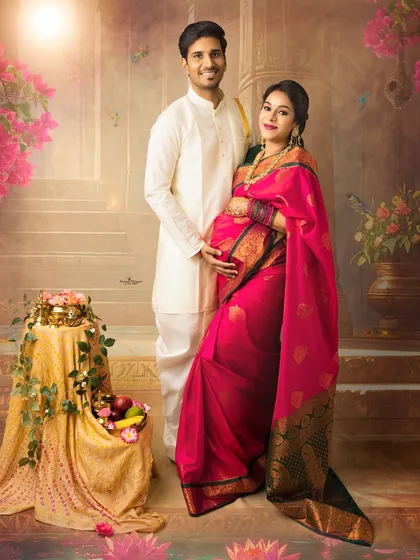 A beautiful standing portrait of an expecting couple. Dressed in elegant traditional wear against a backdrop of painted flowers, they radiate happiness and anticipation.