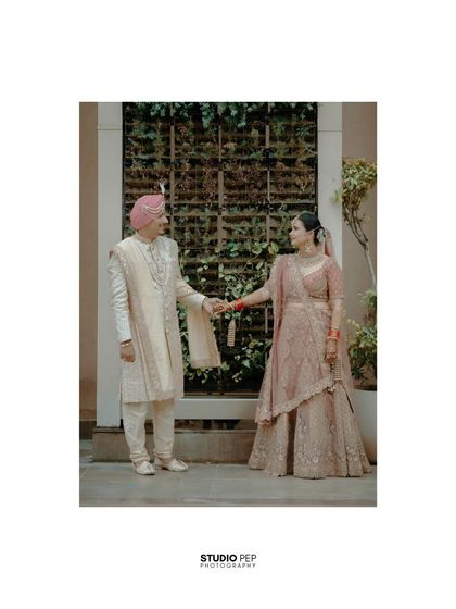 A classic portrait of the couple holding hands, their pastel outfits looking beautiful against the modern architecture.