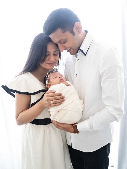 A tender moment between new parents and their baby girl. The classic black and white outfits provide a timeless elegance to this heartwarming family photograph.