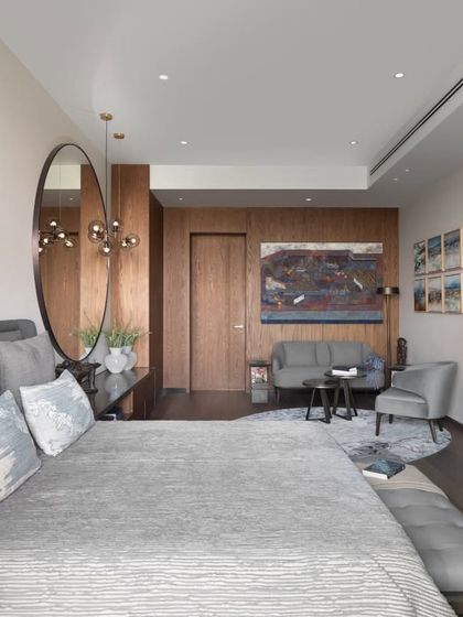 This guest bedroom in the DLF Camellias apartment is designed to be a complete suite, with a comfortable bed, a dedicated TV and media unit, and a small, elegant seating area. The palette is calm and neutral, creating a welcoming and restful environment for any visitor.