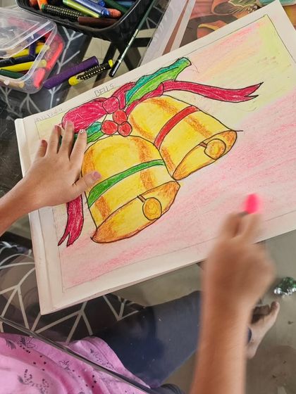 A student hard at work, adding the final touches to her colorful drawing of Christmas bells.