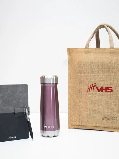 This joining kit for VHS includes a branded jute tote bag, a two-tone notebook with a pen, and a sleek purple Milton water bottle, combining style with sustainable choices.