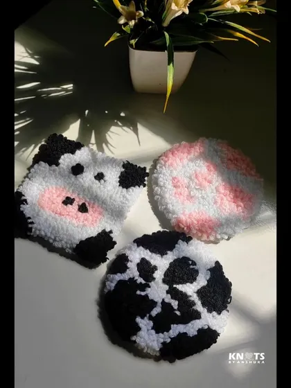 An overhead view of the cow face and cow print punch needle coasters.