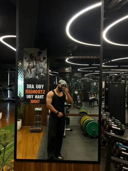 A full view of our gym floor in the mirror. This shot showcases the clean, organized space, with weight plates stacked, cardio machines in the background, and motivational posters on the wall.