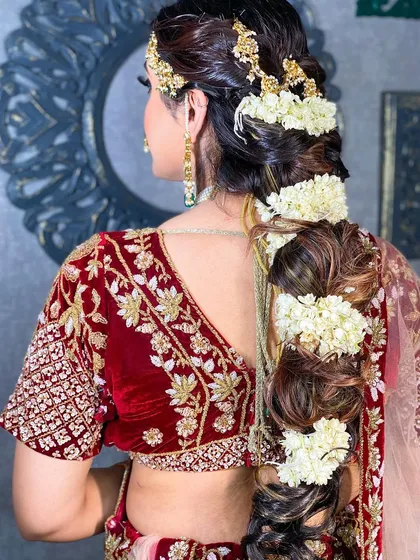 A detailed shot of a beautiful bridal braid, adorned with traditional gajra and a parandi. This showcases the complete look, including expert hairstyling.