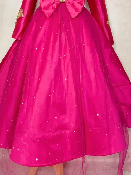 The back of the magenta gown shows the full, flowing skirt, which is sprinkled with subtle sequins for a touch of sparkle as she moves.