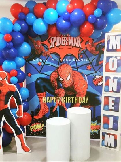 A modern Spiderman theme birthday decoration with personalized name blocks. The setup includes a character cutout and a red and blue balloon arch.