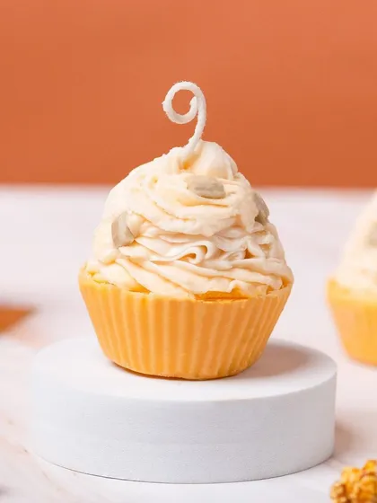 A close-up of a dessert-themed candle from Delight Candles, shaped like a cupcake with frosting. The detail in the candle is the main focus of this shot.