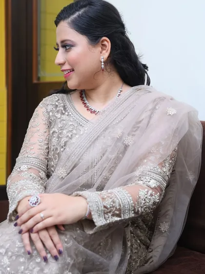 A candid moment. The soft lighting highlights the dewy finish of the makeup and the intricate details of her outfit.