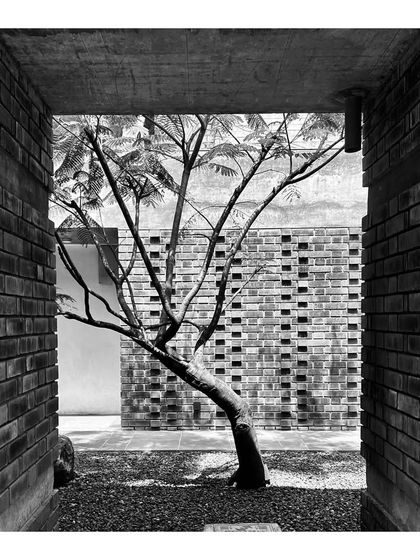 Black and white photographs of a courtyard under construction, focusing on the texture of the brickwork and the framing of a tree. These site visits are crucial for ensuring the quality of construction and the integrity of the design intent.