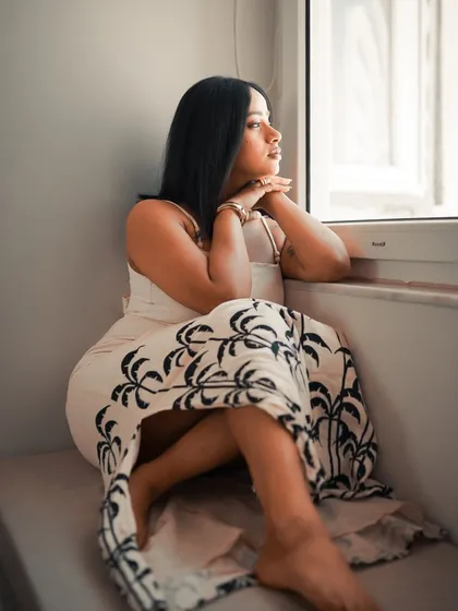 Looking out the window, lost in thought. This is a classic cinematic pose that uses light and shadow to evoke a sense of longing or contemplation.