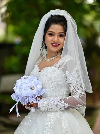 A confident and happy bride, ready to walk down the aisle. The makeup features a classic red lip and defined eyes, a timeless choice for a white wedding.