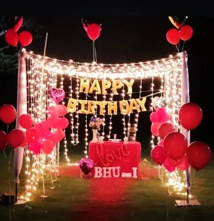For more intimate celebrations, I design romantic outdoor birthday setups like this one. It features a canopy of fairy lights, "Happy Birthday" foil balloons, and simple red balloon decor to create a magical and personal atmosphere.