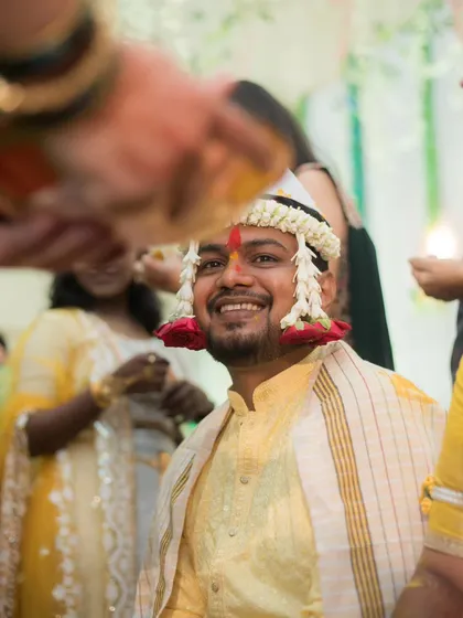 A joyful, candid portrait of the groom smiling as he is blessed during his Haldi ceremony.