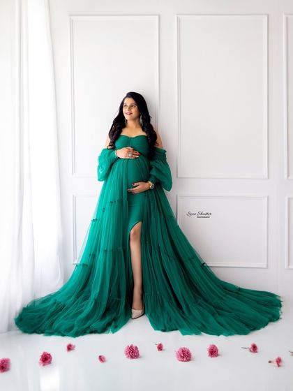 A full-length shot against a clean white backdrop allows the stunning color and volume of this green gown to take center stage. The scattered petals add a romantic touch.
