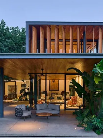 The combination of natural stone, warm wood, and vertical timber fins on the upper level gives the 'Patio House' a rich material palette that is both modern and earthy.