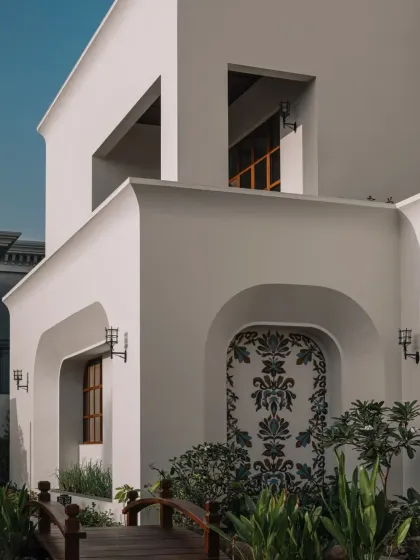 An exterior view showing our glass mosaic fresco set within the clean, arched architecture of a residential project. The artwork serves as a striking focal point, blending traditional craft with minimalist design.