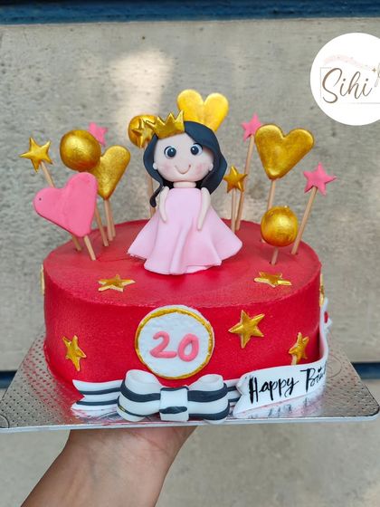 Girly cakes well into your adulthood are a great way to celebrate. This vibrant red cake features a cute princess figurine, surrounded by gold hearts and stars for a fun 20th birthday.