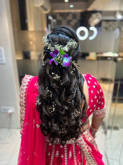 A beautiful open hairstyle with curls, decorated with baby's breath and orchids.