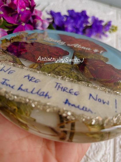 The heart of the story. This is the handwritten note, "We are three now," which I carefully preserved inside a resin plaque along with the flowers that came with it.