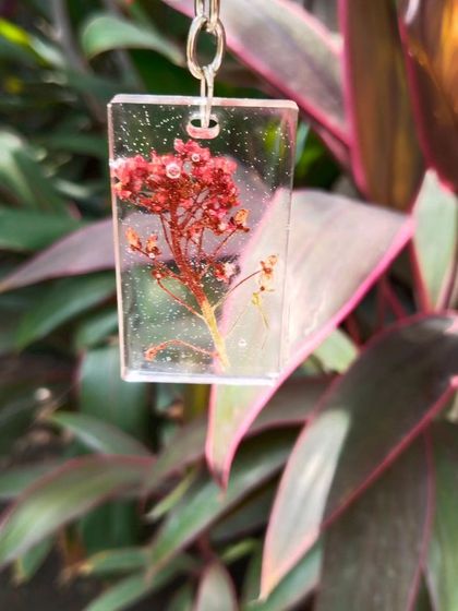 Here is the red baby's breath keychain against a different background, highlighting its vibrant color. Each floral keychain is one-of-a-kind because every flower is unique.