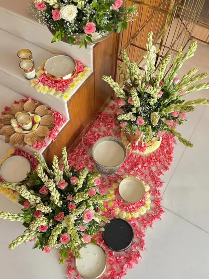 An overhead view of the decorated staircase, showing the artful arrangement of flower petals, candles in various holders, and lush floral bouquets, creating a rich tapestry of festive color and light.