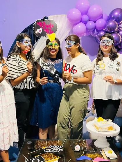 It's all about having fun with the bride tribe. The whole group is posing with fun masks and props in front of the decorated table, ready to cut the cake.
