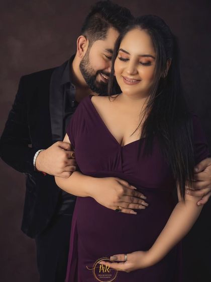 A close-up, intimate portrait of a couple. The partner embraces the expectant mother from behind, both sharing a quiet, happy moment.