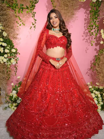 Dressed in a stunning red lehenga, the sister of the groom radiates main character energy. Our team created a glowing, glamorous look to match her vibrant outfit.