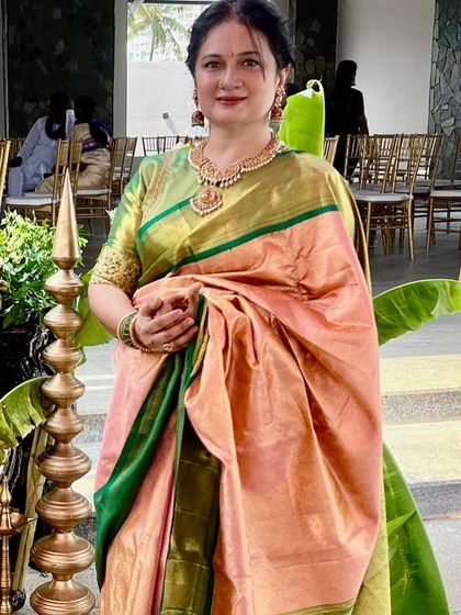 The timeless elegance of our client Vani Reddy, who looks ethereal in this exquisite pale orange and leaf green pure designer silk saree.