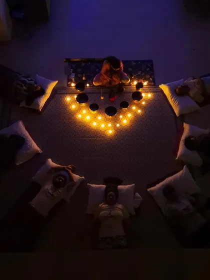 An aerial view of our candlelit sound bath session. Participants lie in a circle, absorbing the healing frequencies of the singing bowls for a deeply restorative experience of Yoga Nidra.