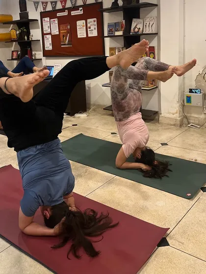 Advanced students explore variations of Sirsasana, the headstand. The TTC environment encourages creative exploration of asanas within a safe and structured framework.