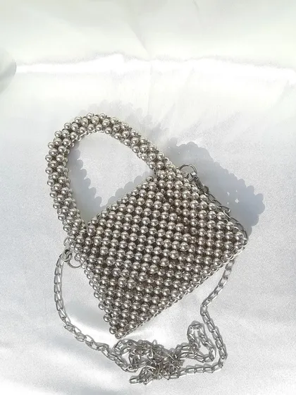 This is my metallic silver beaded mini bag, a small and elegant accessory for evenings out. It features a structured top handle and includes a detachable silver chain strap so it can be worn as a crossbody or shoulder bag.