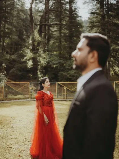 A fairy tale post-wedding moment, with the groom looking at his bride who is dressed in a stunning red gown.